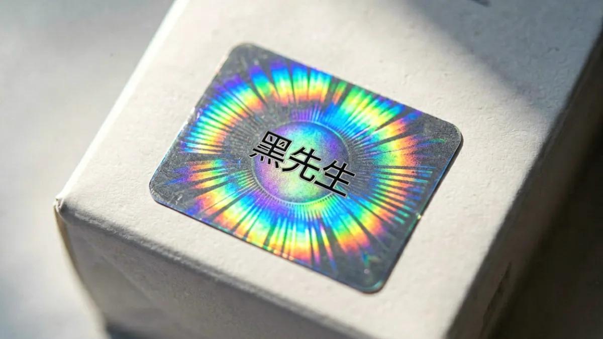 好色先生正品防伪标识近距离特写，激光镭射标签在斜光下呈现彩虹色光晕效果